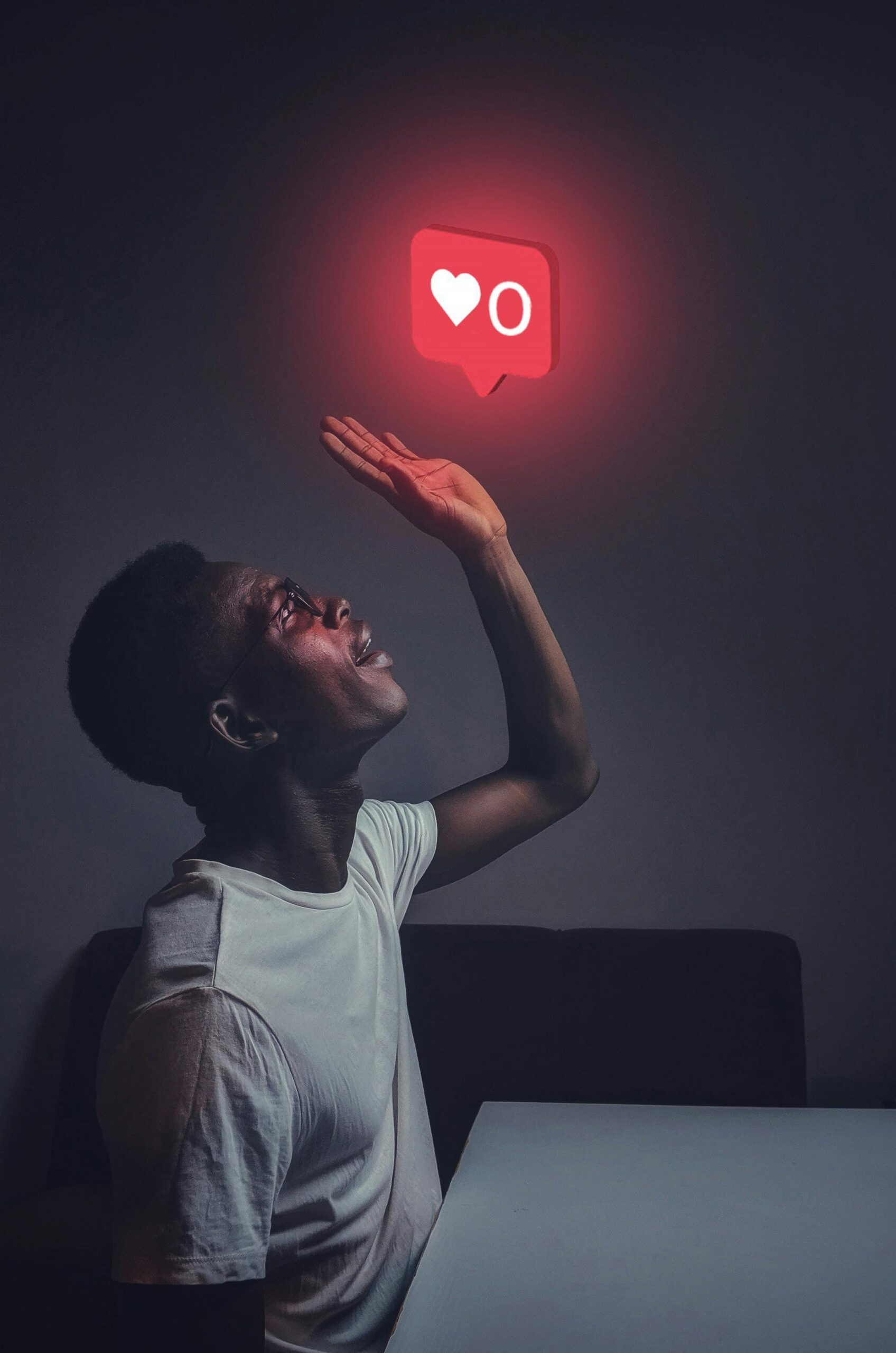 A man sits indoors reaching towards a glowing social media notification icon.